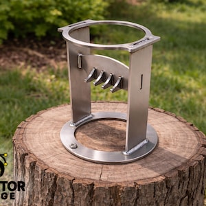 Könnte beinhalten: Ein silberfarbener Metallständer mit kreisförmiger Ober- und Unterseite, der vier gebogene Haken und einen rechteckigen Rahmen aufweist. Der Ständer wird auf einem Baumstumpf präsentiert. Der Text "DVector Forge" ist sichtbar.