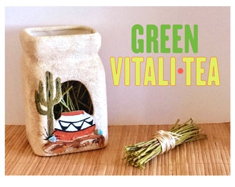 May include: A ceramic jar with a southwestern design, featuring a cactus and a pot, holds a bundle of green tea. The jar is labeled "GREEN VITALI-TEA".