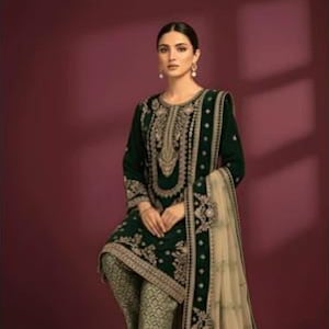 May include: A dark green embroidered outfit with gold accents. The ensemble includes a long-sleeved top, patterned pants, and a flowing scarf. The outfit is embellished with intricate gold embroidery and is suitable for special occasions.