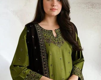 May include: Olive green tunic with black accents and intricate embroidery around the neckline and cuffs. The long sleeves and flowing design create an elegant silhouette. The outfit is adorned with small, sparkling embellishments.