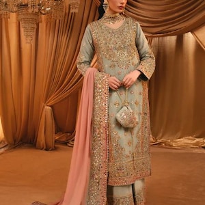 K&ouml;nnte beinhalten: Ein salbeigr&uuml;nes Set aus lang&auml;rmeliger Tunika und weiter Hose mit aufwendigen Goldstickereien, Pailletten und Perlenarbeiten. Das Outfit enth&auml;lt einen passenden salbeigr&uuml;nen Dupatta mit breitem Goldrand und einen kleinen Beutel.