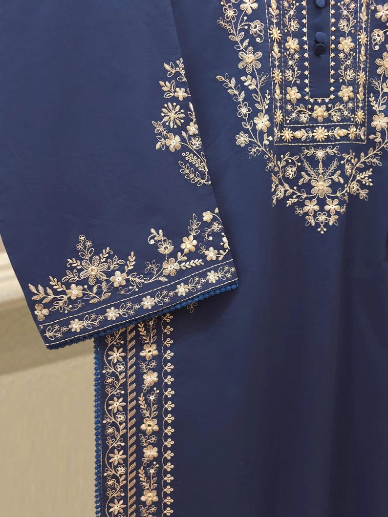 May include: A navy blue garment with intricate gold floral embroidery. The embroidery adorns the neckline, sleeves, and a vertical panel, creating a detailed and elegant design. The sleeves have a delicate trim.