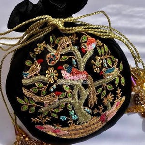 May include: Black velvet drawstring bag with gold embroidery featuring a tree with colorful birds. The birds have red, blue, and pink accents. The bag has gold rope drawstrings and tassels.