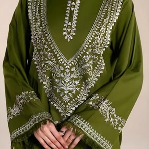 May include: Olive green tunic with long sleeves and intricate white floral embroidery. The embroidery frames the neckline and adorns the cuffs, which are finished with a fringe. A stylish, elegant top.