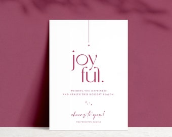 Może przedstawiać: Biała kartka z czerwonym pozdrowieniem 'joy ful'. Kartka ma mały sznurek z diamentem na końcu. Tekst 'Wishing you happiness and health this holiday season' znajduje się pod pozdrowieniem. Kartka jest podpisana 'cheers to you! The Winston Family'.