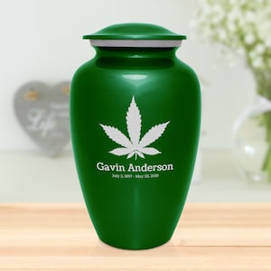 May include: Green metal cremation urn with a white marijuana leaf design and the name "Gavin Anderson" and dates "July 2, 1987 - May 23, 2019" engraved on the front.