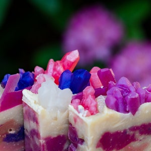 May include: Three bars of handmade soap with a white base and pink, purple, and blue swirls. The soap is topped with colorful crystal-like decorations.