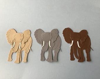 May include: Three paper cutouts of elephants in different colors: beige, gray, and brown. The elephants are facing forward with their trunks raised and their tusks visible.