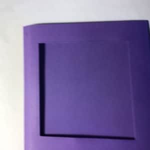 May include: A purple card with a square opening in the center. The card is made of thick paper and has a smooth surface.