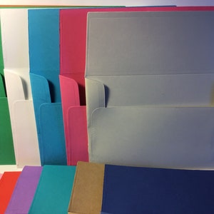 May include: A variety of colored envelopes with a white interior. The envelopes are arranged in a row, with the white interior facing the viewer. The envelopes are all the same size and shape.