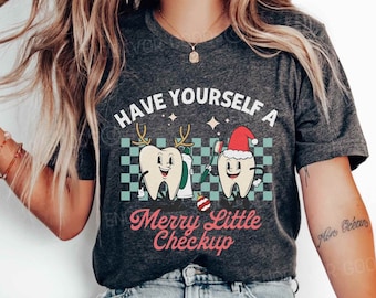 Könnte beinhalten: Dunkelgraues meliertes T-Shirt mit einer Grafik von zwei Zeichentrickzähnen. Einer der Zähne trägt ein Geweih und hält Zahnpasta, der andere trägt einen Weihnachtsmannhut und hält eine Zahnbürste. Der Text lautet "Have Yourself a Merry Little Checkup."