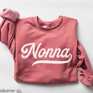 May include: Heather scarlet red sweatshirt with the word "Nonna" printed in white with a vintage style font.