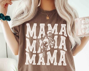 May include: Espresso-colored t-shirt with the word "MAMA" repeated three times in white, along with a graphic of a person riding a horse. The shirt also has the word "ESPRESSO" printed at the bottom.
