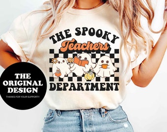 Puede incluir: Camiseta de color marfil con la frase "The Spooky Teachers Department" sobre un gráfico de tres personajes fantasma. Los fantasmas sostienen una calabaza, un libro y flores. La camiseta también tiene el texto "The Original Design".