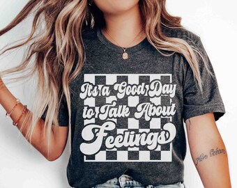 May include: A gray t-shirt with a white checkered background and the text "It's a Good Day to Talk About Feelings" in a retro font.