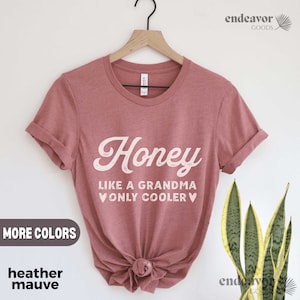 May include: Heather mauve t-shirt with the text "Honey Like a Grandma Only Cooler" in a white, vintage-style font. The shirt is displayed on a hanger, with the words "More Colors" and "heather mauve" in a box.
