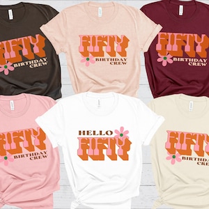 May include: Five t-shirts with a retro-style graphic that says "Fifty Birthday Crew" in orange and pink letters with a small pink flower. The shirts are in brown, pink, maroon, white, and beige.