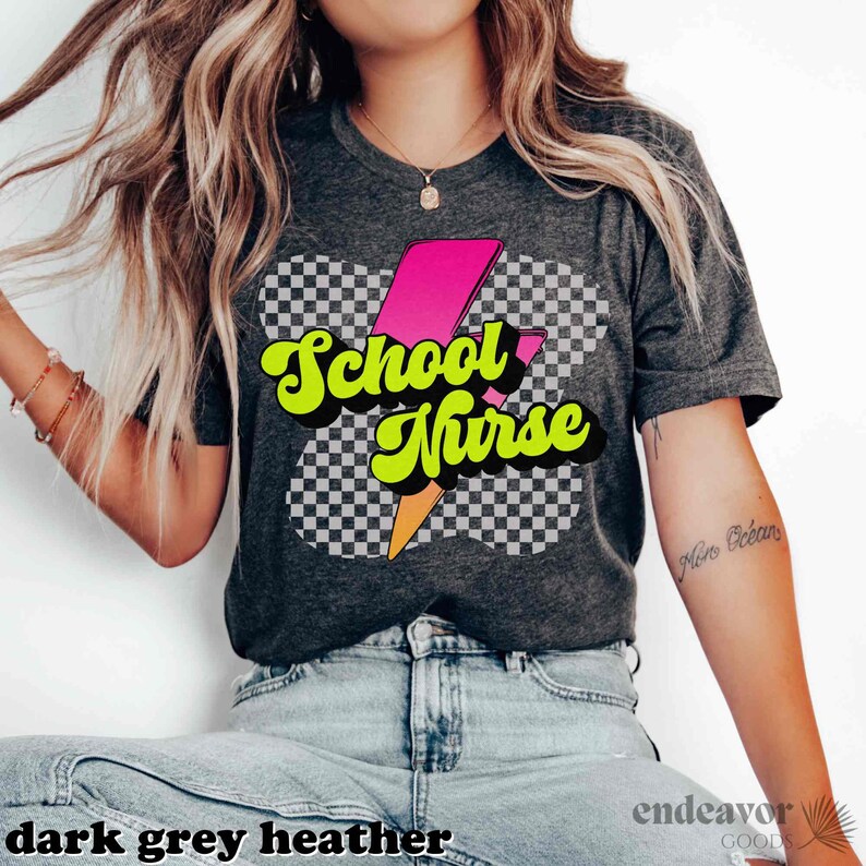 Op de afbeelding: Een donkergrijs heather t-shirt met een retro-grafische afbeelding van een bliksemflits en de tekst "School Nurse" in gele en roze letters.