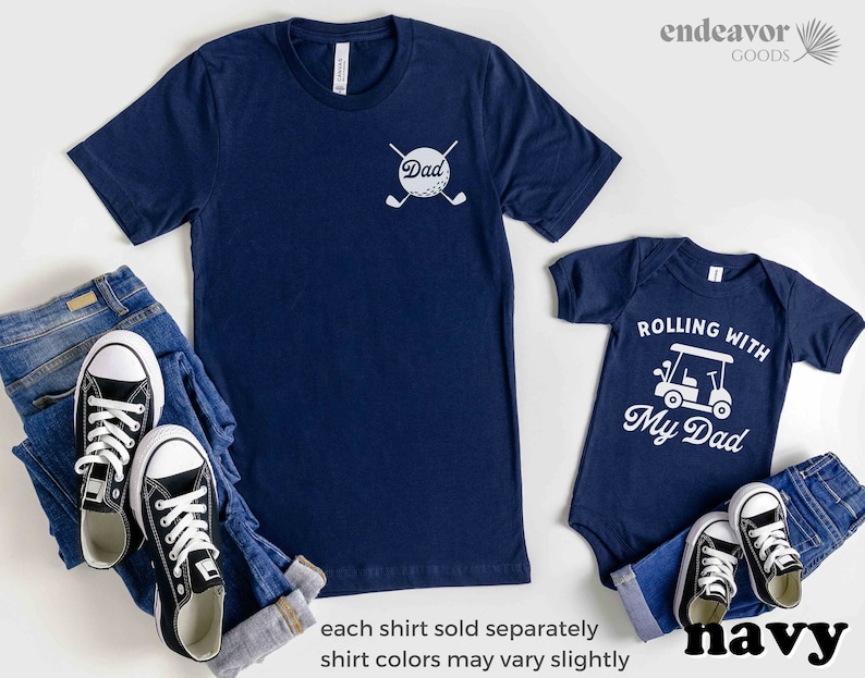 May include: Matching navy blue t-shirts for a father and child. The father's shirt has a white golf ball with crossed golf clubs and the word "Dad". The child's shirt has a white golf cart with the text "Rolling with My Dad".