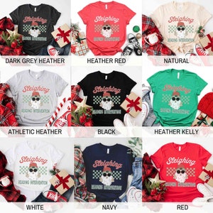 K&ouml;nnte beinhalten: Ein Set aus zehn T-Shirts mit einem Weihnachtsmann, der eine Sonnenbrille und eine M&uuml;tze tr&auml;gt und den Text "Sleighing Reading Intervention" zeigt. Die T-Shirts sind in verschiedenen Farben erh&auml;ltlich, darunter dunkelgrauer Heather, roter Heather, Natur, sportlicher Heather, Schwarz, gr&uuml;ner Heather, Wei&szlig;, Marineblau und Rot.