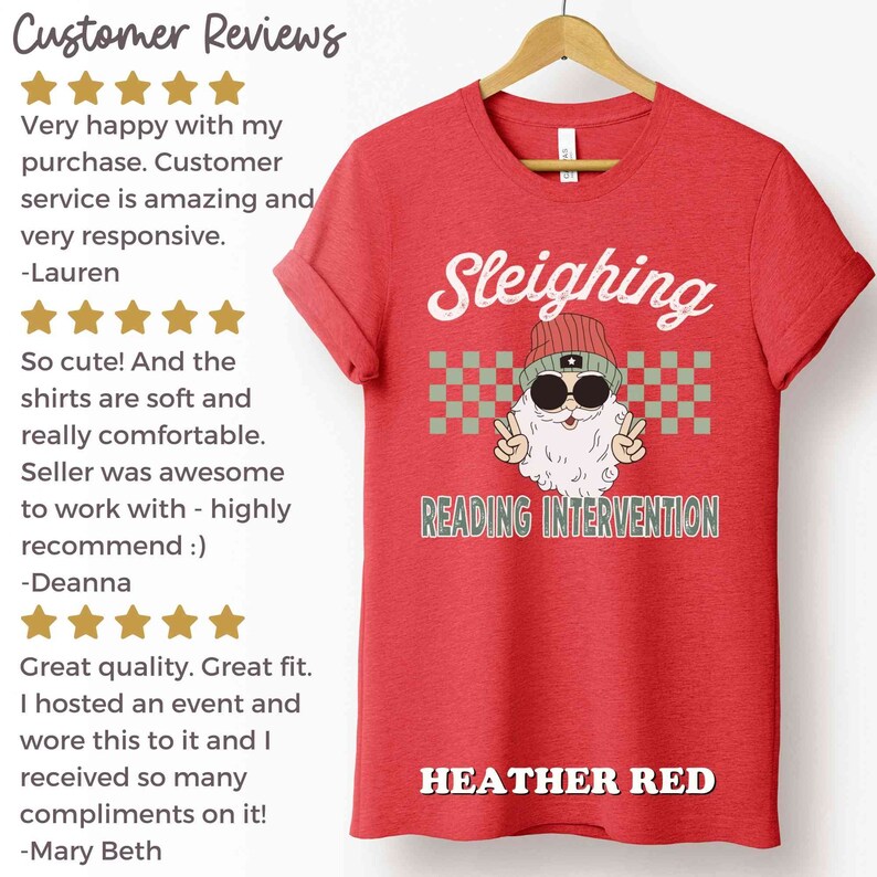 K&ouml;nnte beinhalten: Rotes T-Shirt aus Heather-Material mit einer wei&szlig;en Grafik eines Weihnachtsmanns mit Sonnenbrille und M&uuml;tze. Unter der Grafik steht der Text "Sleighing Reading Intervention".