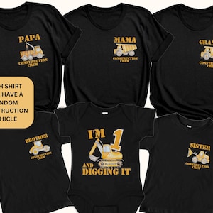 May include: Black t-shirts and a baby onesie featuring construction-themed designs. Shirts display "Papa," "Mama," "Grandma," "Brother," and "Sister," each with a construction vehicle. The onesie reads "I'm 1 and Digging It."