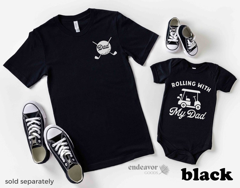 May include: Black t-shirts with a golf-themed design. The adult shirt says "Dad" with a golf ball and clubs. The baby shirt says "Rolling with My Dad" with a golf cart.