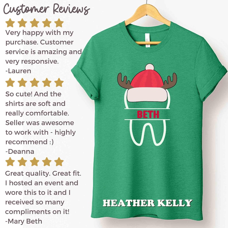 以下が含まれることがあります： 赤と白の帽子と角、名前「BETH」、名前「HEATHER KELLY」の白い文字が特徴の、お祝いのデザインの緑色のTシャツ。木製のハンガーにシャツが表示されています。