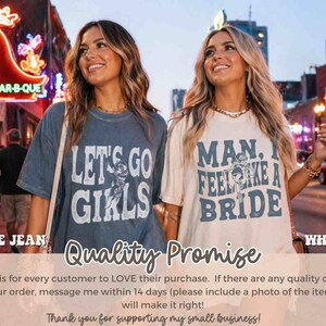 K&ouml;nnte beinhalten: Zwei Frauen tragen Grafik-T-Shirts. Eines ist blau mit dem Text "LET'S GO GIRLS", das andere ist wei&szlig; mit dem Text "MAN, I FEEL LIKE A BRIDE". Der Hintergrund zeigt eine Stadtstra&szlig;e mit Neonreklamen.