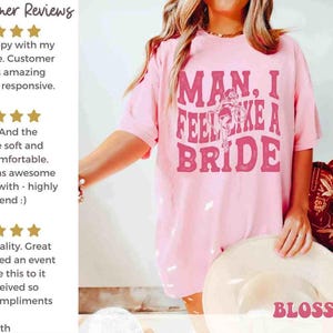 K&ouml;nnte beinhalten: Hellrosa T-Shirt mit dem Text "MAN, I FEEL LIKE A BRIDE" in einem Retro-Schriftstil. Das Shirt hat eine Braut-Grafik. Das Bild zeigt auch rote Cowboy-Stiefel und einen wei&szlig;en Hut.