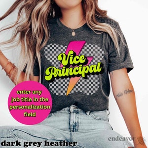 K&ouml;nnte beinhalten: Ein dunkelgraues T-Shirt aus Heather-Material mit einer Grafik im Retro-Stil, die "Vice Principal" in gelben und pinken Buchstaben mit einem Blitz-Design zeigt. Der Text "enter any job title in the personalization field" ist ebenfalls im Bild enthalten.