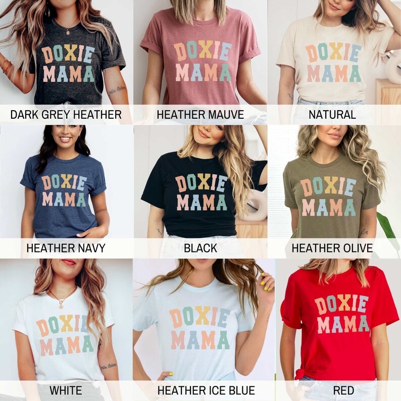 May include: A collection of t-shirts in various colors, each featuring the text "DOXIE MAMA" in a colorful, retro font. The shirts are displayed on models, showcasing the different color options available, including dark grey, mauve, natural, navy, black, olive, white, ice blue, and red.