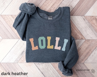 May include: A dark heather grey sweatshirt with the word "LOLLI" printed in a rainbow arch design.