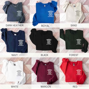 May include: A set of nine sweatshirts in various colors, each featuring a white graphic of a police badge with the text "Thermostat" and "Protect & Serve". The colors include dark heather, royal blue, sand, navy, black, forest green, white, maroon, and red.