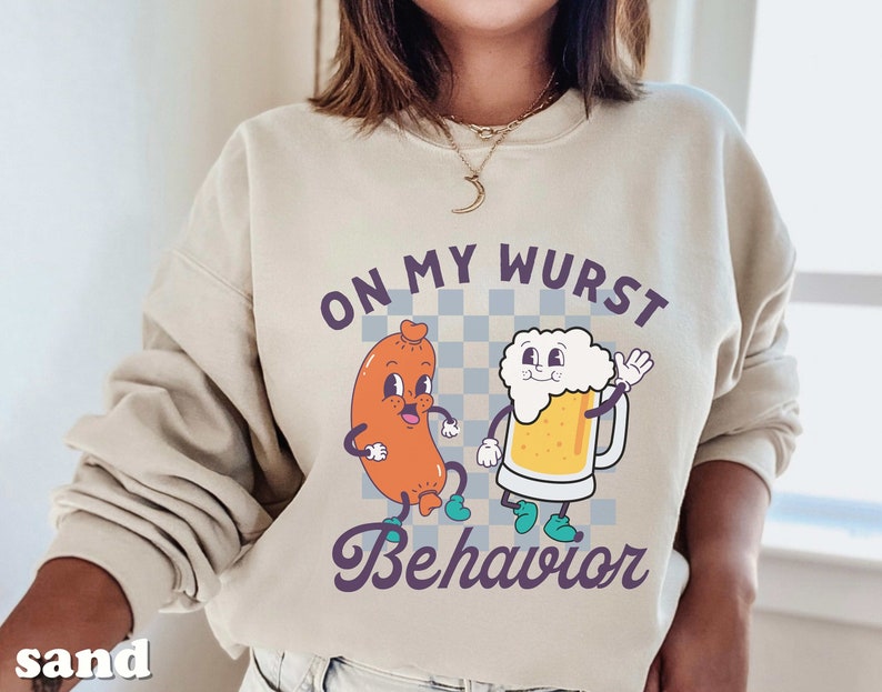 May include: A beige sweatshirt with a cartoon sausage and beer graphic. The text on the sweatshirt reads "On My Wurst Behavior".