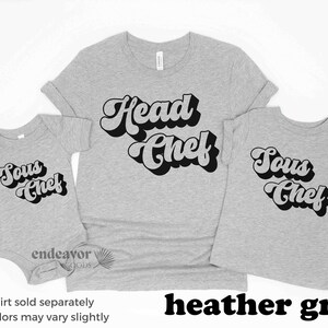 K&ouml;nnte beinhalten: Drei T-Shirts in Heather Grey mit Retro-Schriftzug. Das gr&ouml;&szlig;te T-Shirt sagt "Head Chef", das mittlere T-Shirt sagt "Sous Chef" und das kleinste T-Shirt sagt "Sous Chef".