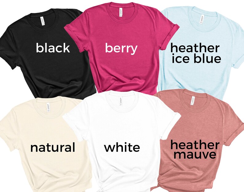 May include: Six t-shirts in different colors, including black, berry, heather ice blue, natural, white, and heather mauve. Each shirt has a different color name printed on the front.