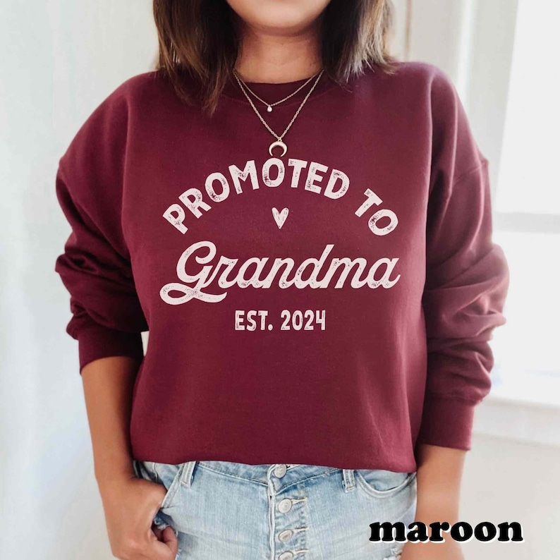 May include: Maroon sweatshirt with the text "Promoted to Grandma Est. 2024" in white lettering.