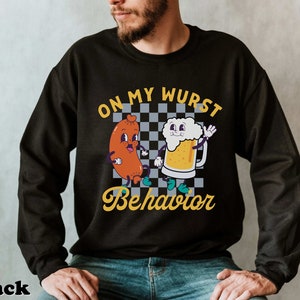 May include: Black sweatshirt with a graphic of a cartoon sausage and beer mug. The text "On My Wurst Behavior" is printed on the shirt.