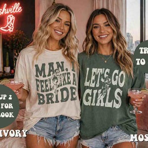 K&ouml;nnte beinhalten: Zwei Frauen tragen Grafik-T-Shirts und Jeansshorts. Eines ist elfenbeinfarben mit dem Text "MAN, I FEEL LIKE A BRIDE", das andere ist moosgr&uuml;n mit "LET'S GO GIRLS". Im Hintergrund ein Neon-Schild "Nashville" und ein gerahmtes Schild.