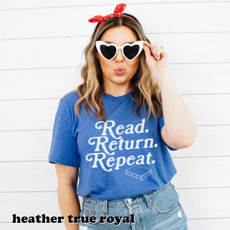 May include: A blue t-shirt with the words "Read. Return. Repeat." in white script. The shirt also features a small book graphic. The model is wearing heart-shaped sunglasses and a red bandana.