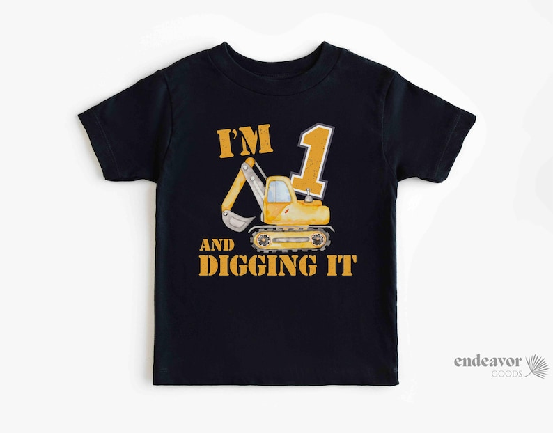May include: Black toddler t-shirt featuring a yellow excavator graphic and the text "I'M 1 AND DIGGING IT". The design includes a large number 1 and a cartoon excavator.