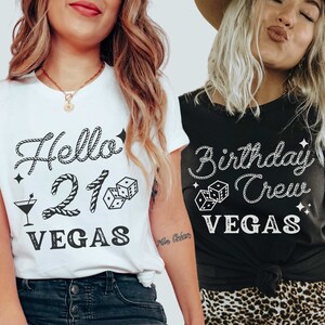 May include: Two women wearing matching t-shirts with a Vegas birthday theme. The white shirt says "Hello 21 Vegas" with a rope design, dice, and a martini glass. The black shirt says "Birthday Crew Vegas" with a rope design and dice.