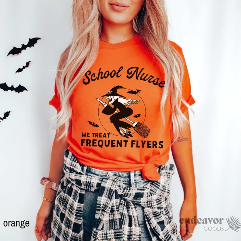 May include: Orange t-shirt with a black graphic of a witch flying on a broomstick with the text "School Nurse We Treat Frequent Flyers".