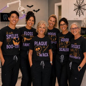 May include: A group of six black t-shirts featuring Halloween-themed dental graphics and text in purple and orange. The shirts display phrases including I make SMILES BOO-TIFUL, FLOSS your FANGS, PLAQUE is WACK, HOCUS POCUS, SCARY GOOD with the SCALER, and no TRICKS just TREAT(MENT)S.