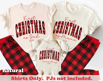 May include: Two off-white t-shirts and one baby bodysuit featuring red and black buffalo plaid text that reads First Christmas as Dad, First Christmas as Mama, and First Christmas Emma May 2026. The set includes red and black plaid pants.