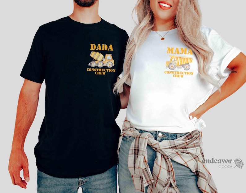 May include: Matching black and white t-shirts with construction-themed graphics. The black shirt says "DADA CONSTRUCTION CREW" with a yellow cement mixer. The white shirt says "MAMA CONSTRUCTION CREW" with a yellow dump truck.