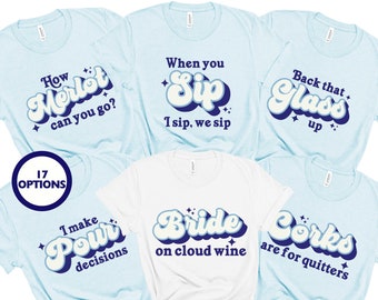 May include: Seven light blue and white t-shirts with a retro font design. The shirts feature phrases like "How Merlot can you go?", "When you Sip, I sip, we sip", "Back that Glass up", "I make Pour decisions", "Bride on cloud wine", and "Corks are for quitters".