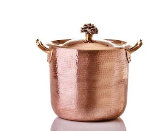 May include: A hammered copper pot with a brass knob and handles. The pot has a rounded bottom and a wide opening.