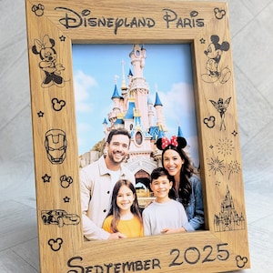 May include: Wooden photo frame with the text "Disneyland Paris" and "September 2025" engraved. The frame features Disney character illustrations and holds a family photo in front of a castle.